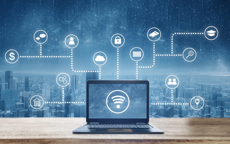Computer laptop on wooden desk with wireless and application programming and social media icons. Internet networking and wireless technology